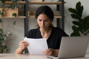 Woman looking concerned while reviewing credit report at home
